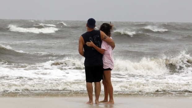 A couple watches as waves break along the beach