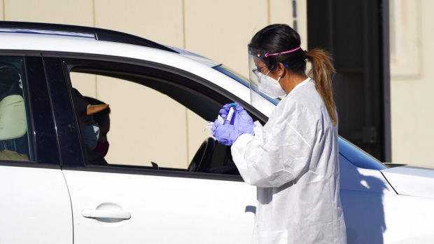 Tester administers swab test at drive-in testing site.