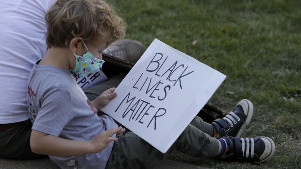 A white child holds a Black Lives Matter sign at a protest