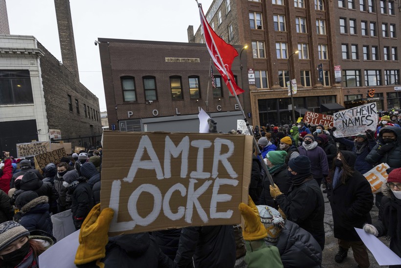 Demonstrators march past a police precinct during a rally