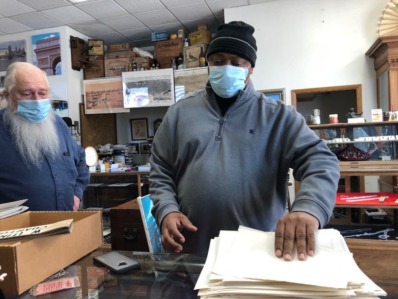 A man stands at a counter with a stack of documents 