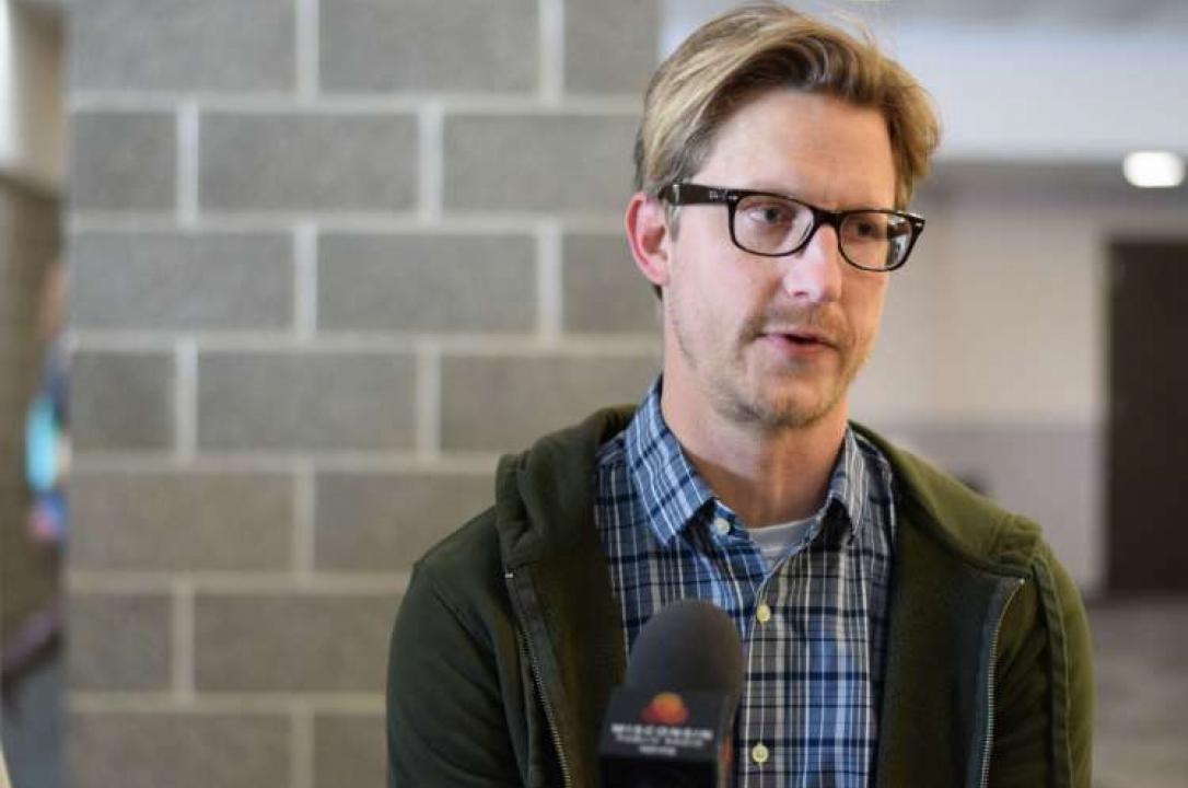 A serious-looking, bespectacled Eric Blumreich speaks into the WPR microphone